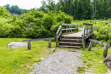Wooden bridge and creek at Gettysburg battlefield national park landscape during summer with green field