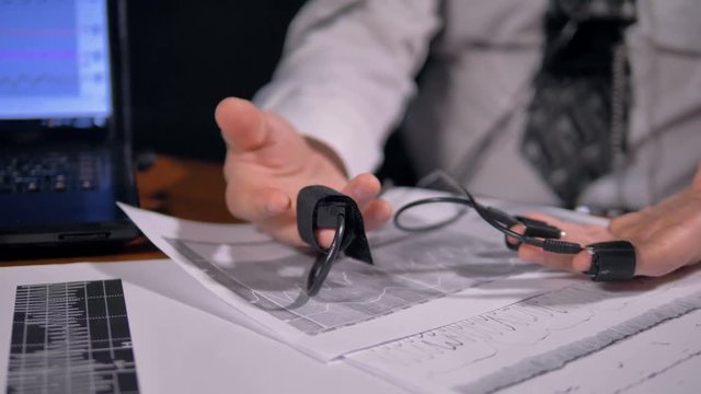 Male hands with polygraph sensors lying over data sheets. 4K 60 fps.