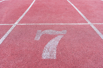 White Number seven athletic track number on red rubber racetrack, texture of running racetracks in stadium
