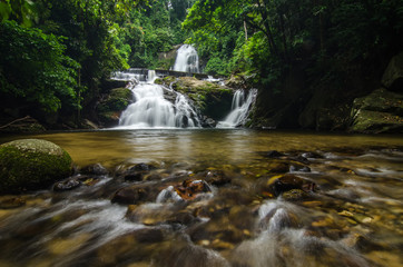 tropical nature background, waterfall stream and surrounded by green forest