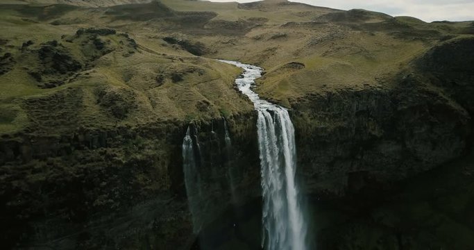 Aerial view to the mountains river flows through the valley and falls down. Waterfall Seljalandsfoss in Iceland.