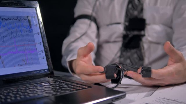 Trembling hands connected to polygraph sensors.