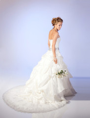 Charming bride holding a bouquet of flowers on a light background. Positive emotions.