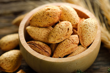 Almonds in a bowl on wooden background