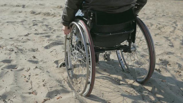 Disabled man in wheelchair, makes failed attempts steer wheelchair, over obstacle, handicapped Rides sand, Difficulty traveling wheelchair, invalid person on wheel chair stuck in sand, Difficult