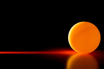 Yellow ball on a red dark background illuminated by a side beam of light