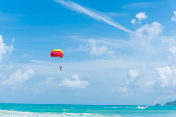 People enjoy parasailing water sport, Flying on a parachute behind a boat on a summer holiday by the sea at Patong beach. The most famous tourist attraction in Phuket province, Thailand.