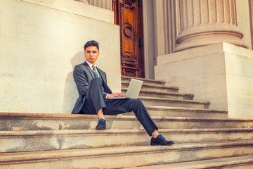 Young Asian American Business Man working on laptop computer outside in New York