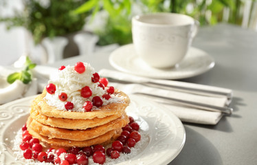 Stack of delicious coconut pancakes with butter cream, berries and shavings on table