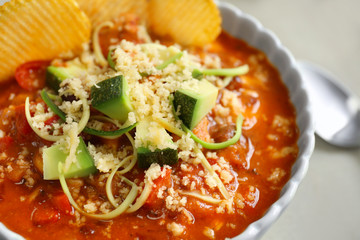 Bowl with delicious chili turkey, avocado slices, grated cheese and chips on table, closeup