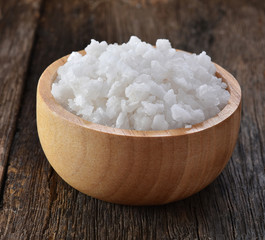 Salt in a cup on a wooden background.