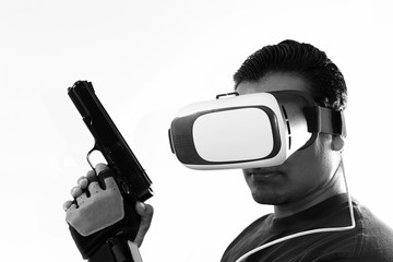 Young gamer wearing virtual reality goggles holding gun pistol