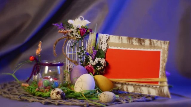 Wooden Photo Frames and a Set of Slide Cards Put Near a White Top Egg Cage and a Bottle With a Lit Candle in It, as Well as Easter Hen and Quail Eggs