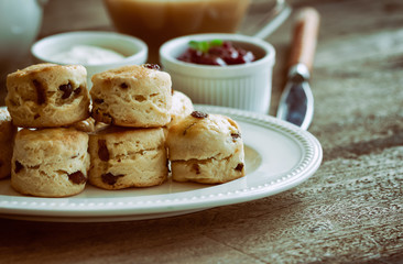 Homemade raisin scones serve with homemade strawberries jam,clotted cream and tea.Scones is English pastry for afternoon tea,cream tea.Delicious scones Devon shire or Cornish cream style.