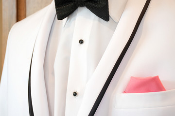 white tuxedo with black bow tie and pink handkerchief in pocket