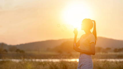 Happy woman blowing bubbles  in meadow.
