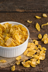 close up white bowl of cornflakes on sackcloth  on wooden background with copy space ,still life , in concept breakfast