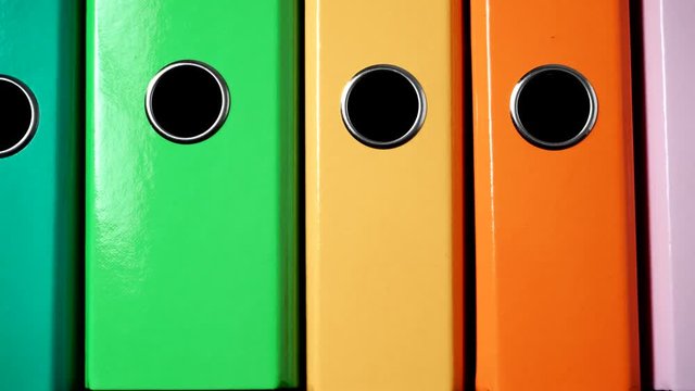 Close up of many colorful file folders, ring binders as vivid color office background. Dolly slider shot 4K ProRes HQ codec