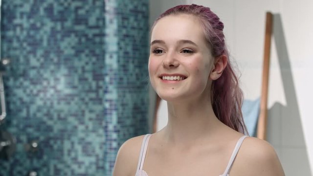 Young girl in puberty examining her armpits with a happy look