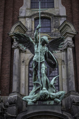 Skulptur des Erzengel Michael im Kampf gegen Satan an einem Kirchturm in Hamburg