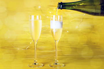 Champagne poured into glasses on golden background
