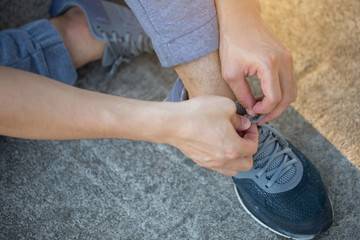 Young Asian man putting on pair of shoes, Tie the laces on the shoes