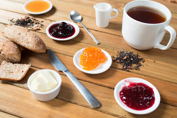 Crispy rolls with butter, jam and hot tea for breakfast