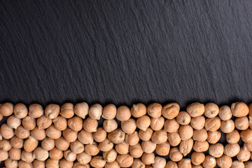 Chickpeas lies on a black stone board, space for text, black background