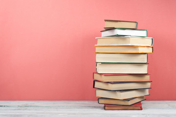 Open stacking book, hardback colorful books on wooden table, red, pink background. Back to school. Copy space for text. Education business concept.