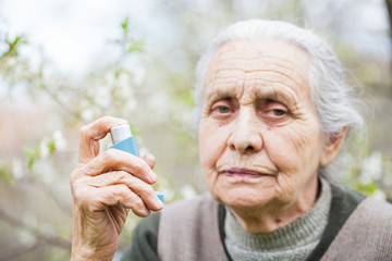 Elderly woman having asthma attack, holding a bronchodilator
