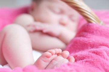 feets of sleeping newborn closeup. Infant baby girl  lying on pink blanket in basket. Cute soft...