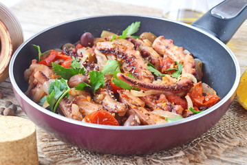 Octopus cooked in olive oil with olives, oregano, tomatoes, capers, lemon in a frying pan. Healthy eating. Mediterranean lifestyle