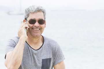 Senior man talking on the phone at the beach