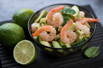 Close-up of avocado salad with tiger shrimps and cucumber, selective focus