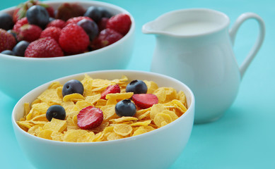 Corn flakes, milk and fresh fruits as blueberries and strawberries prepared for healthy breakfast. Close up view.