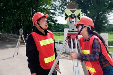Surveyor or Engineer making measure by Theodolite with partner on the field.