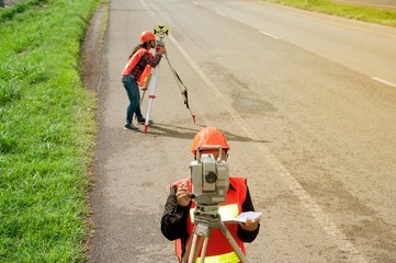 Surveyor or Engineer making measure by Theodolite with partner on the highway.