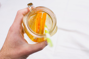 Man drinking water with orange in glass jar