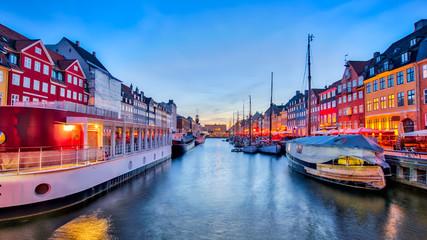 Nyhavn with its picturesque harbor with old sailing ships and colorful facades of old houses in...