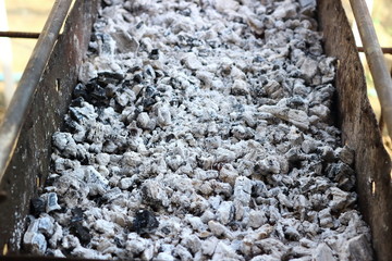 Photo of fire ashes,dark grey black coal,background texture. Wood burning in ashes. Coal flame fires,cooking barbecue.Ashes mineral cube stone,bbq grill flaming hot charcoal briquettes,fracture coals.