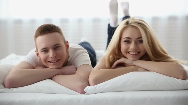 Happy young couple in love laying on the bed