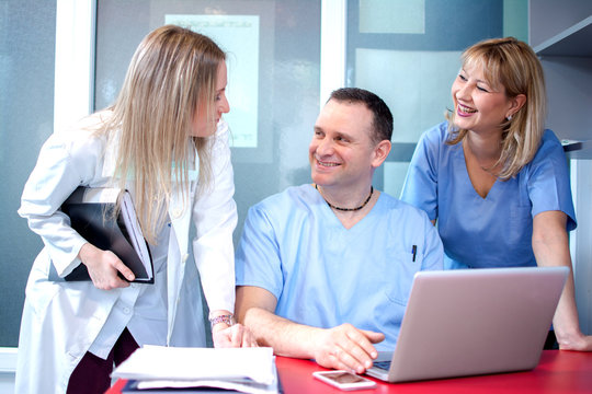 Small Group Of Doctors Working Together In Doctor's Office.