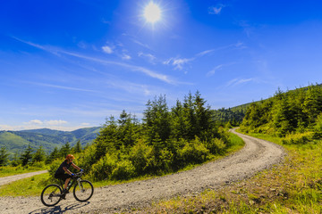 Mountain biking women riding on bike in summer mountains forest landscape. Woman cycling MTB outdoor sport activity.