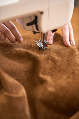 Female tailor threading leather material on sewing machine
