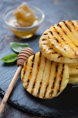 Closeup of barbecued pineapple slices topped with honey, selective focus, shallow depth of field