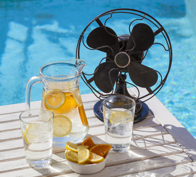 Hot Summer Day During A Heat Wave. A Jar Of Refreshing Water And A Vintage Fan At The Pool.