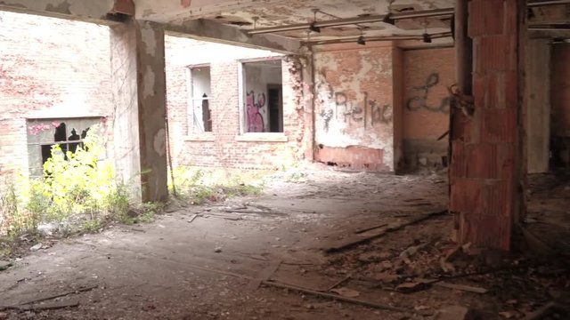 FPV, CLOSE UP: Walking along dark narrow hallway in abandoned crumbling block of flats in decaying ghost town. Weathered wooden doors and peeling paint on the walls in chaotic haunted house in America