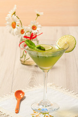 Kiwi jelly with lime pieces in the glass and bouquet of chamomiles on the background