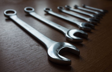 Set of metal wrenches on a wooden background.
