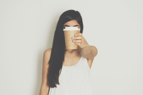 Woman holding brown paper cup of hot coffee.